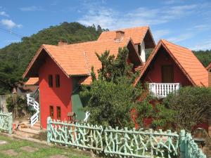 una casa roja con una valla blanca delante en Villa da Vila, en Monte Verde