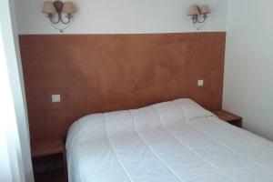 - une chambre avec un lit blanc et une tête de lit en bois dans l'établissement casa-anghjulina, à Porto-Vecchio