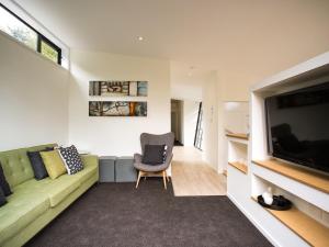 a living room with a green couch and a television at The Treehouse - Kaiteriteri Holiday Home in Kaiteriteri