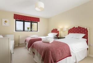 Duas camas num quarto com lençóis vermelhos e brancos em Fairfields em Moreton-in-Marsh
