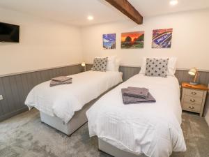 two twin beds in a room with a tv at Nana's Cottage in Camborne