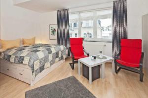 um quarto com cadeiras vermelhas, uma cama e uma mesa em Villa Seestern Wohnung 9 em Neuhof
