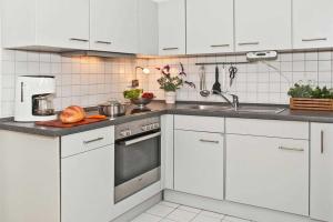 uma cozinha com armários brancos e um forno com placa de fogão em Villa Seestern Wohnung 9 em Neuhof