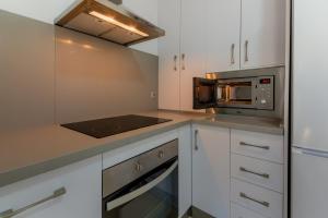 a kitchen with white cabinets and a microwave at Villas Flamenco Beach Conil in Conil de la Frontera