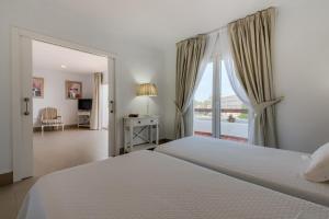 a white bedroom with a bed and a window at Villas Flamenco Beach Conil in Conil de la Frontera