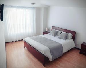 um quarto com uma cama grande e uma janela grande em Nogal Suite Hotel em Pasto