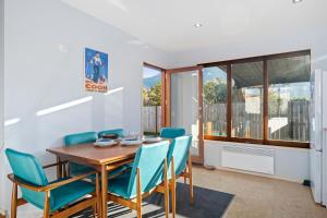 a dining room with a wooden table and blue chairs at Lake Hawea Haven - Lake Hawea Holiday Home in Lake Hawea
