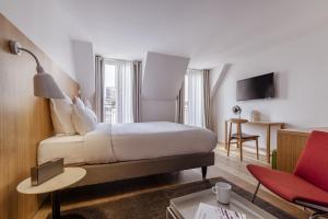 a hotel room with a bed and a red chair at 9Hotel Republique in Paris