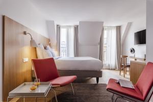 パリにある9ホテル レピュブリックのベッド1台と赤い椅子2脚が備わるホテルルームです。