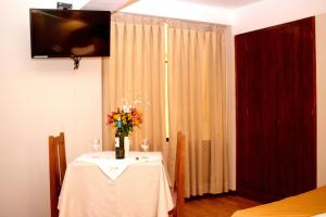 un tavolo bianco con un vaso di fiori sopra di Hotel Vilandre a Cuzco