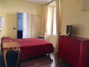 a bedroom with a red bed and a tv on a dresser at Villa Romantica Hotel in Limone sul Garda