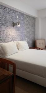 a white bed sitting in a room next to a wall at Boa Nova Guesthouse in Lisbon