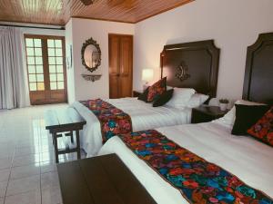 a hotel room with two beds and a table at Hacienda Escondida 10min to Airport in Alajuela