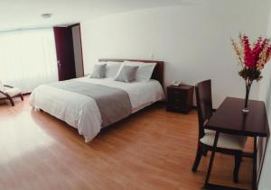 a bedroom with a bed and a table and a desk at Nogal Suite Hotel Pasto in Pasto