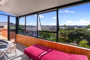 a balcony with a bed and a large group of windows at Serene at Snells - Snells Beach Bach in Snells Beach