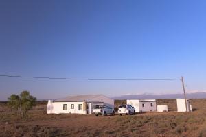 a house and two vehicles parked in a field at Karoo Secret in Aberdeen