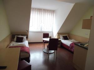 a hotel room with two beds and a table at Hotel Gasthof zum Engel - Gästehaus in Künzelsau