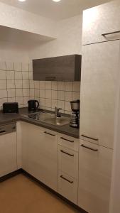 eine Küche mit weißen Schränken und einer Spüle in der Unterkunft Ferienwohnung Sölden bei Freiburg im Breisgau in Sölden