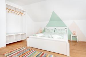 a white bedroom with a bed with a geometric headboard at Menta Porta in Zengővárkony