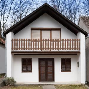 Cette maison blanche dispose d'un balcon en bois. dans l'établissement Menta Porta, à Zengővárkony