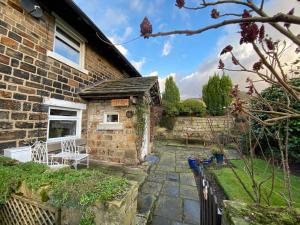 a brick house with a garden and a patio at Hawkshead Cottage in Glossop