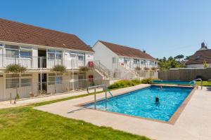 a pool with a person in it in a yard with houses at Ilex Lodge in St Peter Port
