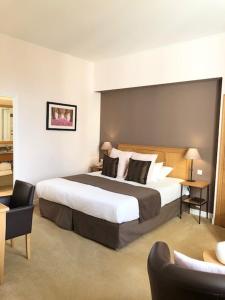 - une chambre avec un grand lit dans une chambre d'hôtel dans l'établissement Hôtel Saint-Laurent, The Originals Relais, à Montfort-lʼAmaury