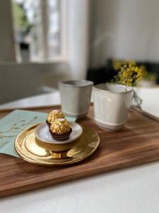 - un gâteau sur une assiette sur un plateau en bois avec deux tasses dans l'établissement B&B Het Atelier, à Doesburg
