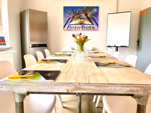 une salle de conférence avec une longue table en bois et des chaises blanches dans l'établissement Seerose Boutique-Pension, à Tating