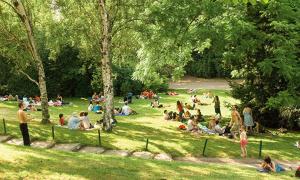 Un gruppo di persone sedute nell'erba in un parco di COSY HOME APPART entre Paris et Disney Land a Fontenay-sous-Bois