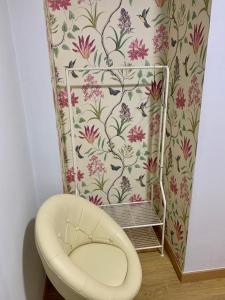 een badkamer met een stoel en bloemrijk behang bij Apartamentos Maladeta in Benasque