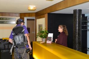 un hombre con una mochila y una mujer parada en un mostrador en Hotel Rotes Haus en Brugg