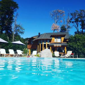 una casa con piscina frente a una casa en El Raulí del Bonito en Villa La Angostura