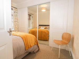 a bedroom with a bed and a chair and a mirror at Cosy Bee in Morecambe