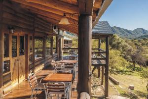 a deck with tables and chairs on a cabin at Los Ancares Resort in Mina Clavero