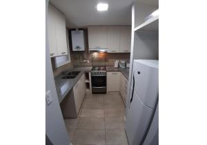 Elle comprend une petite cuisine avec des placards blancs et un réfrigérateur. dans l'établissement Departamento en el centro de Bariloche bb, à San Carlos de Bariloche