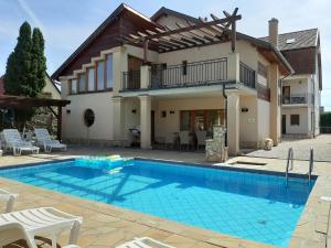 a swimming pool in front of a house at Família Apartmanház in Keszthely