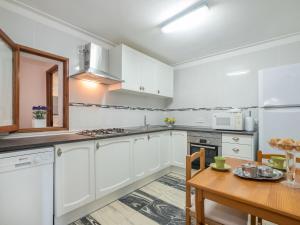 a kitchen with white cabinets and a wooden table at Apartment Voramar by Interhome in Alcudia