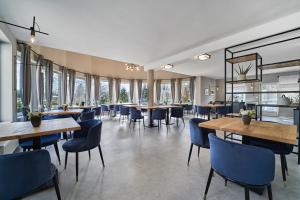 ein Restaurant mit Tischen, Stühlen und Fenstern in der Unterkunft Hotel Arborétum in Harkány
