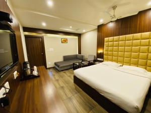 a bedroom with a bed and a couch and a television at Saluja Residency in Siliguri