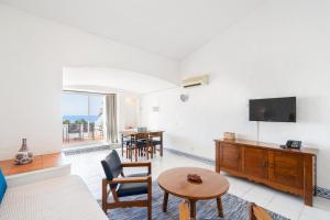 a living room with a couch and a tv and a table at Apartamentos Borda D´Agua in Albufeira