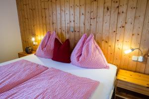 Schlafzimmer mit einem Bett mit rosa Bettwäsche und Kissen in der Unterkunft Ferienwohnung Thurn-ummerstall in Hollersbach im Pinzgau