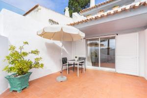 a patio with a table and an umbrella at Apartamentos Borda D´Agua in Albufeira