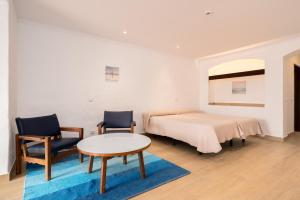 a bedroom with a bed and two chairs and a table at Apartamentos Borda D´Agua in Albufeira