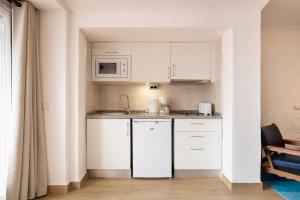 a small kitchen with white cabinets and a microwave at Apartamentos Borda D´Agua in Albufeira