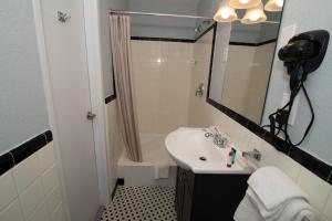 a bathroom with a sink and a shower and a mirror at The Minuteman Inn Acton Concord Littleton in Acton