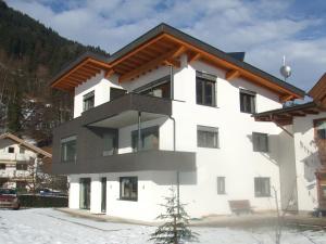 - un bâtiment blanc avec un toit en bois dans l'établissement apArtment kAtrin & gerhArd, à Schwendau