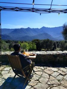 Ein Mann sitzt auf einem Stuhl und blickt auf die Berge. in der Unterkunft L'Aghjalle in Santa-Reparata-di-Balagna