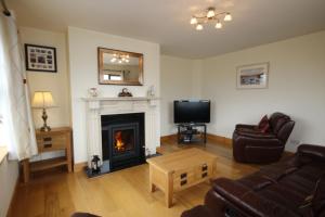 sala de estar con chimenea y TV en King's Lodge en Cleggan