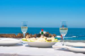 a table with a plate of food and two wine glasses at La Mer Seafront Selfcatering Accommodation Kleinmond in Kleinmond